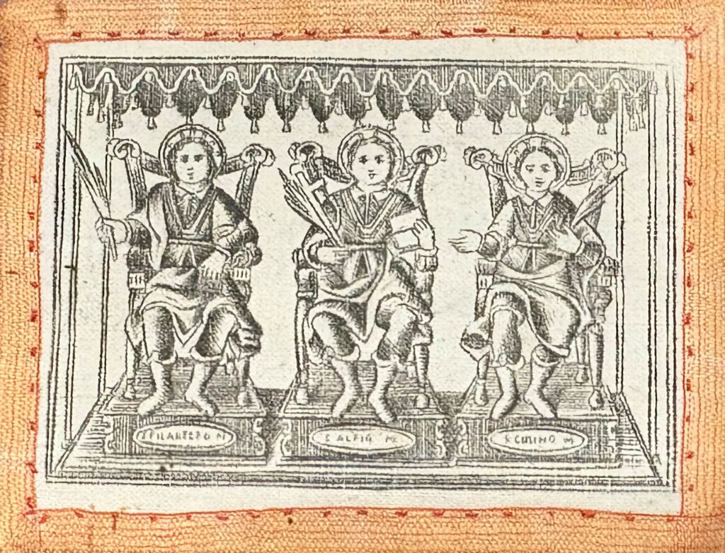 A woven cloth showing three haloed saints, with ‘S Alfio’ written beneath the middle figure.